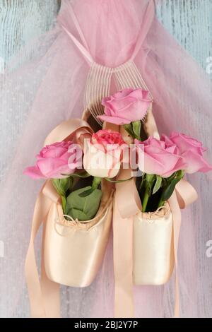 Chaussures de ballet décorées avec des roses en elle accrochées sur fond bleu en bois Banque D'Images