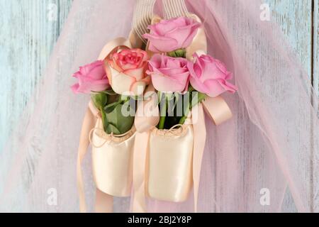 Chaussures de ballet décorées avec des roses en elle accrochées sur fond bleu en bois Banque D'Images