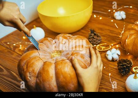 Gros plan sur la citrouille de la main de l'homme pour Halloween sur une table rustique en bois. Concept d'automne. Banque D'Images