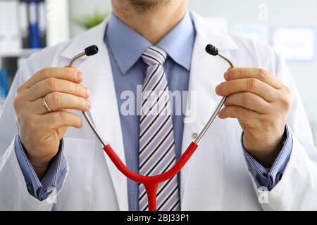 Les mains du médecin de médecine masculine tiennent et mettent sur stéthoscope Banque D'Images