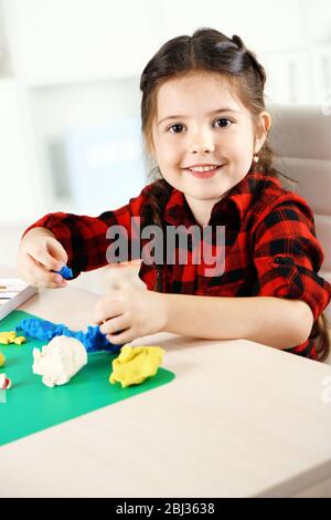 Cute little girl moules de la pâte à modeler sur la table Banque D'Images