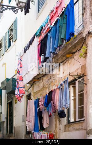 Scène typique de rue escarpée portugaise, buanderie suspendue pour sécher sur les lignes de lavage dans une allée étroite dans le district d'Alfama, Lisbonne, Portugal Banque D'Images