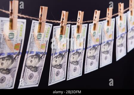 Concept de blanchiment d'argent - cent factures pendent sur un cordon contre fond gris