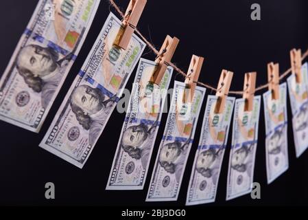 Concept de blanchiment d'argent - cent factures pendent sur un cordon contre fond gris