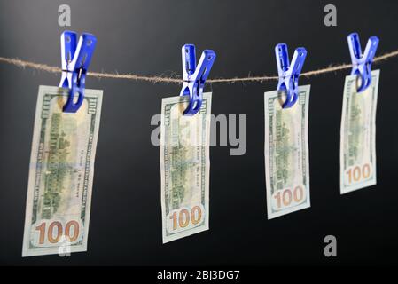 Concept de blanchiment d'argent - cent factures pendent sur un cordon contre fond gris