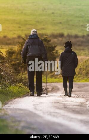 Un couple d'âge mûr se promenant le long d'une route de campagne en soirée à Cornwall. Banque D'Images