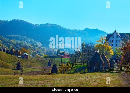 Un paysage pittoresque de la campagne roumaine, une vue panoramique dans un village rural avec des haystacks, des arbres et des montagnes en arrière-plan, calme pla Banque D'Images