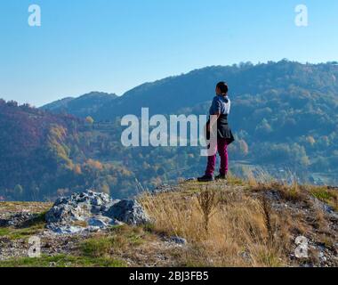 Femme debout au sommet d'une colline, en regardant la distance vers les montagnes, paysage serein tout en randonnée dans la campagne roumaine, randonnée Banque D'Images