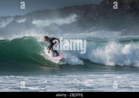 Surf spectaculaire action comme une jeune femme monte un vague à surfer dans Fistral Newquay en Cornouailles. Banque D'Images