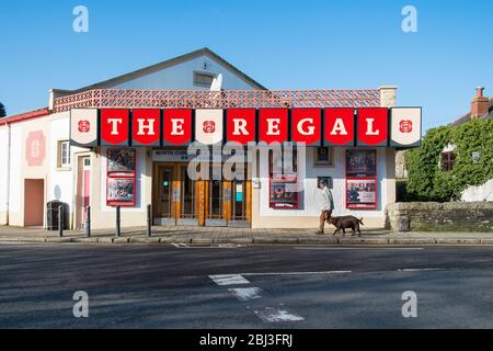 Un homme et ses chiens marchent devant l'extérieur coloré du cinéma Regal historique du centre-ville de Wadebridge, à Cornwall. Banque D'Images