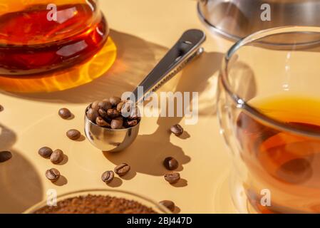 Cuillère en métal avec grains de café torréfiés, lumière dure, préparation du café Banque D'Images