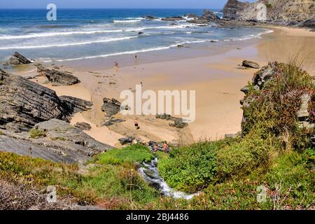 Les gens jouent dans le torrent qui descend de la falaise à la plage Praia do Carvalhal. Solo Backpacker Trekking sur la Rota Vicentina et le tr des pêcheurs Banque D'Images