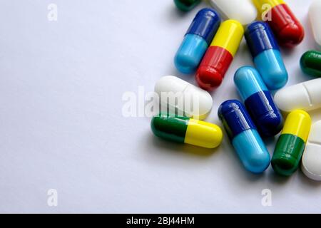 Pile de pilules de différentes couleurs: Bleu, jaune, rouge et blanc) placée sur le dessus du papier blanc. Illustration pour les sujets médicaux, sanitaires et autres. Ma Banque D'Images