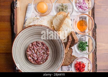 Tartare de boeuf avec œufs, oignons et épices sur la plaque dans le restaurant. Banque D'Images