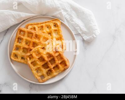Gaufres salées parfait keto. Deux ingrédients chaffles sur plaque sur fond de marbre blanc. Les œufs et le fromage parmesan bas carb gaufres. Vue de dessus ou de télévision. L'espace pour copier du texte ou dessin. Banque D'Images
