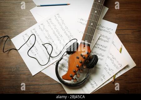 Guitare électrique et casque avec notes musicales sur fond en bois Banque D'Images