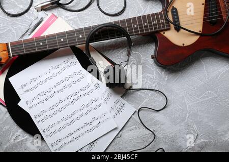 Guitare électrique et casque avec notes musicales sur fond gris Banque D'Images