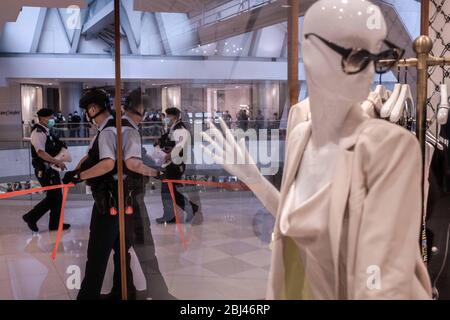 Hong Kong, Chine. 28 avril 2020. Un agent de police porte un masque chirurgical et tient un ruban isolant pendant l'action dans le centre commercial de la SFI. Mardi soir, la police a lancé une tentative de protestation dans le centre commercial de luxe de la SFI, dans le centre. Des officiers ont fait le don d'une partie de l'atrium et plusieurs billets à pénalité fixe ont été émis aux gens pour bafouer les règles de distanciation sociale. Les règles interdisent les rassemblements publics de plus de quatre personnes en raison de la pandémie de Covid-19. Crédit: SOPA Images Limited/Alay Live News Banque D'Images