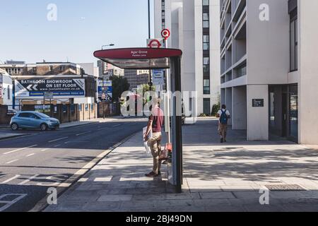 Londres/UK-26/07/18: Un homme qui attend un bus sur l'arrêt Agar Grove sur Caledonian Road dans l'Islington. Un arrêt de bus est un endroit désigné où les bus s Banque D'Images