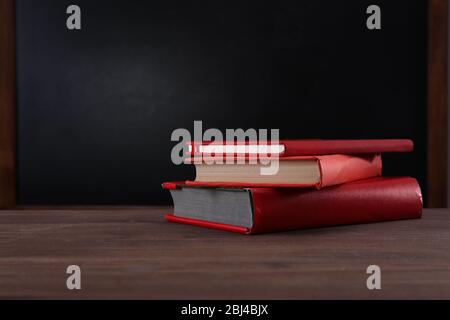 Matériel scolaire sur le bureau sur fond de tableau noir Banque D'Images