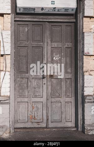 Double porte en bois gris à l'eau de panneaux encadrés avec surface de décollement de peinture écaillée. Architecture de la ville européenne. Extérieur du bâtiment rétro. Banque D'Images