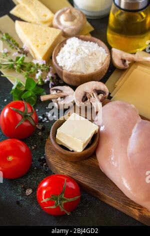 Cuisine italienne. Ingrédients pour la cuisson de lasagnes avec poulet et champignons sur fond de pierre sombre. Banque D'Images