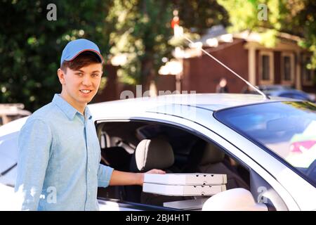 Livraison de pizza garçon près de la voiture Banque D'Images