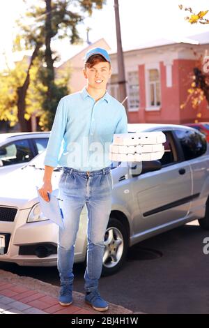 Livraison de pizza boîte de conservation avec pizza près de la voiture Banque D'Images