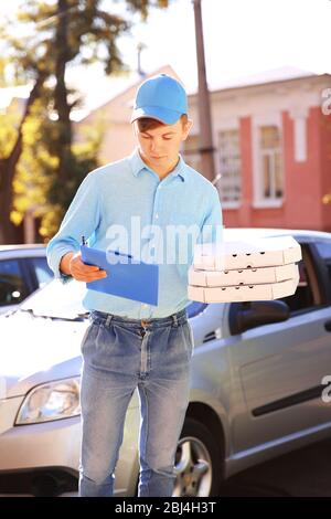 Livraison de pizza boîte de conservation avec pizza près de la voiture Banque D'Images