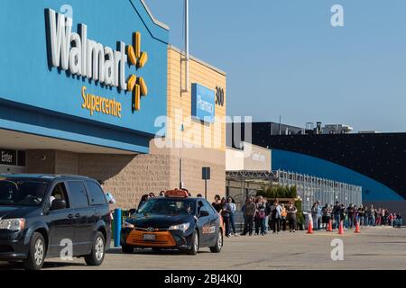 Face à une Superstore Walmart avec des personnes alignées à l'extérieur en raison de la pandémie mondiale de COVID-19 et des directives de distanciation sociale. Banque D'Images