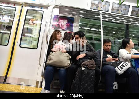 Les parents avec leur jeune enfant prennent un train pour rentrer à la maison et utiliser leur smartphone pour divertir l'enfant, à Tokyo Japon. Banque D'Images