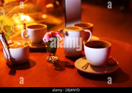 Table en bois servie avec des tasses de café et de sucre dans la rue la nuit Banque D'Images