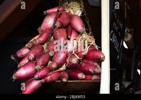 Récolte d'oignons rouges, séchés et tressés pour stockage et vente pendant le marché de la foire, festival alimentaire. Des cordes d'oignon pendent dans une rue ou Banque D'Images