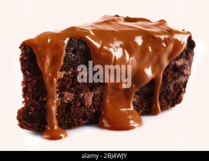 Chocolat versé sur un morceau de gâteau isolé sur blanc Banque D'Images