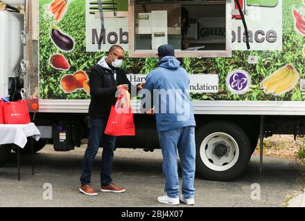 Bridgeport, CT, États-Unis. 28 avril 2020. CHARLES GRADY (à gauche), l'un des fondateurs de la Hang Time à but non lucratif bénéficiant aux anciens détenus, distribue de la nourriture à Bridgeport, dans le Connecticut. Le temps de suspension est une organisation de base qui soutient les récemment incarcérés, avec de la nourriture, de la bourse, de l'aide pour obtenir un emploi, et d'autres services de soutien. La nourriture est offerte avec l'aide du Centre pour l'équité alimentaire et le développement économique du Conseil des Églises du Grand Bridgeport et de la Harvard Pilgrim Healthcare Foundation. Crédit: Stan Godlewski/ZUMA Wire/Alay Live News Banque D'Images