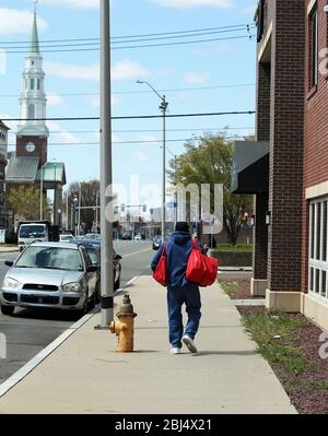 Bridgeport, CT, États-Unis. 28 avril 2020. Un client se rend chez lui après avoir reçu de la nourriture de Hang Time, une organisation de base soutenant les récemment incarcérés, avec de la nourriture, la bourse, aider à obtenir un emploi, et d'autres services de soutien. La nourriture est offerte avec l'aide du Centre pour l'équité alimentaire et le développement économique du Conseil des Églises du Grand Bridgeport et de la Harvard Pilgrim Healthcare Foundation. Crédit: Stan Godlewski/ZUMA Wire/Alay Live News Banque D'Images