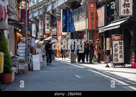 People plewaitting en ligne pour une place dans un restaurant de rue dans le marché Ameyoko, Tokyo, Japon Banque D'Images