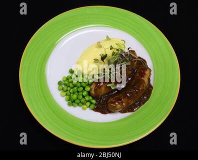 bangers et purée avec sauce à l'oignon et petits pois Banque D'Images