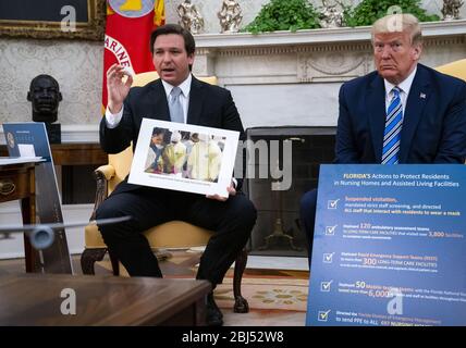 Washington, États-Unis. 28 avril 2020. Le président Donald Trump se penche sur la façon dont le gouverneur de la Floride Ron DeSantis fait des remarques lors d'une réunion au Bureau ovale, le mardi 28 avril 2020. Photo de Doug Mills/UPI crédit: UPI/Alay Live News Banque D'Images