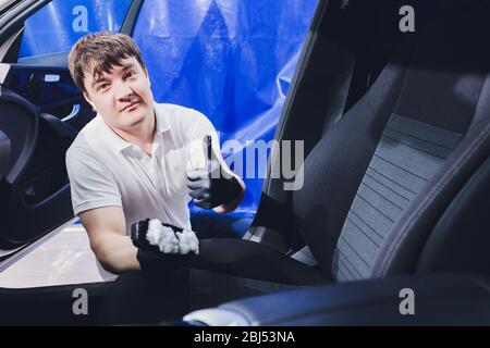 Travailleur de gants est une brosse de lavage avec des sièges de voiture Banque D'Images