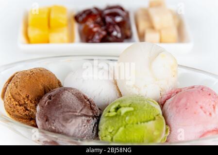 Vue latérale sur le gros plan crème glacée multicolore dans un plat clair et des fruits sucrés transformés pour manger ensemble dans le style thaïlandais, ensemble de glace colorée Banque D'Images