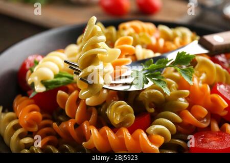 Délicieux plat macaroni dans un bol noir sur une table en bois servie, gros plan Banque D'Images