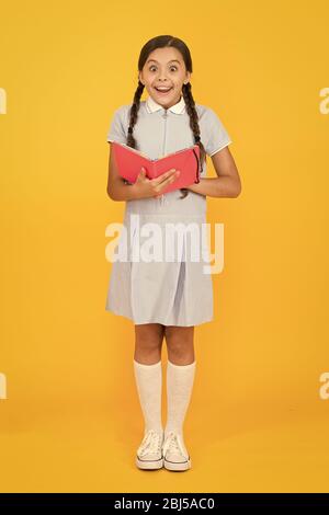 Histoire fascinante. petite fille amour littérature. vieille école. happy little girl en rétro vintage kid fashion. uniforme. retour à l'école. petite fille tenir cahier ou bloc-notes. encyclopedia livre pour enfants. Banque D'Images