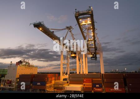 Miami, États-Unis - 01 mars 2016 : conteneurs dans le port de fret. Conteneurs et grues illuminés au crépuscule. Conteneur d'expédition. Service de conteneur. Banque D'Images