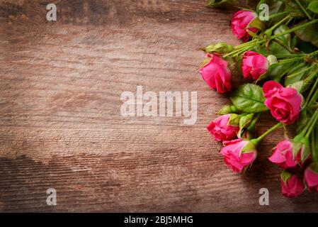 Beau bouquet de roses roses sur fond en bois, espace de copie Banque D'Images