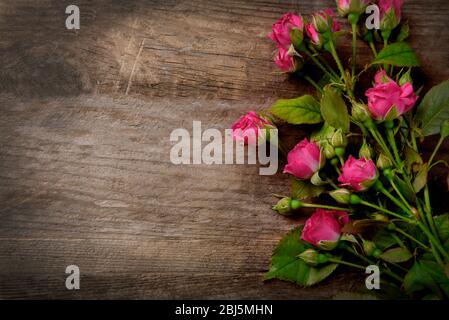 Beau bouquet de roses roses sur fond en bois, espace de copie Banque D'Images