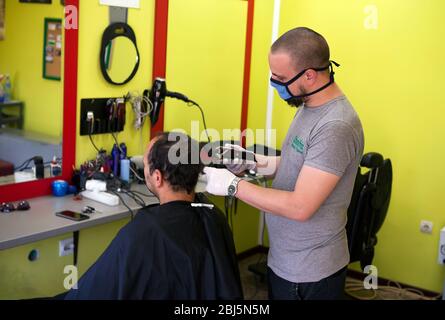 Belgrade, Serbie. 28 avril 2020. Le coiffeur avec masque de protection et gants coupe les cheveux du client après la réouverture pendant la maladie du coronavirus (COVID-19). Le Président serbe Aleksandar Vucic avait déclaré l'état d'urgence pour arrêter la propagation du coronavirus. Suite à la baisse du nombre de patients coronavirus le gouvernement de cette semaine permet la réouverture des coiffeurs, des gyms et des marchés. Crédit: Nikola Krstic/Alay Live News Banque D'Images