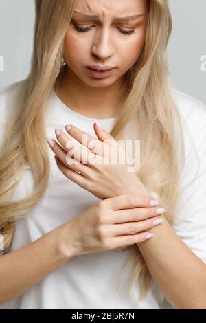 Gros plan portrait de la jeune femme tenant son poignet douloureux causé par un travail prolongé sur l'ordinateur, ordinateur portable. Syndrome du tunnel carpien, arthrite, neurol Banque D'Images