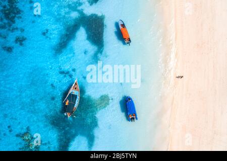 Vue aérienne du bateau de pêche dans l'eau bleu clair au coucher du soleil Banque D'Images