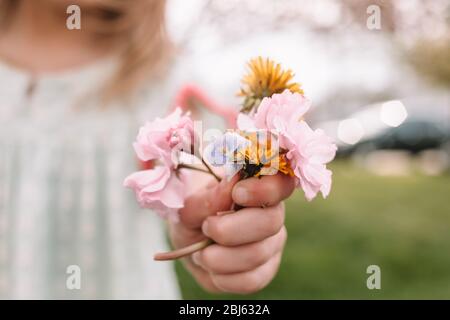 petite fille tenant un petit bouquet de fleurs sauvages et de mauvaises herbes Banque D'Images